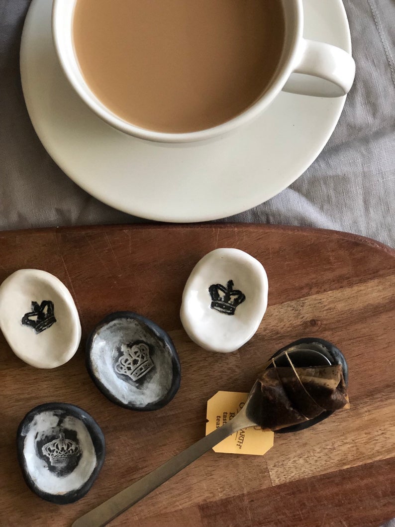 Small white clay teaspoon rest with black crown.